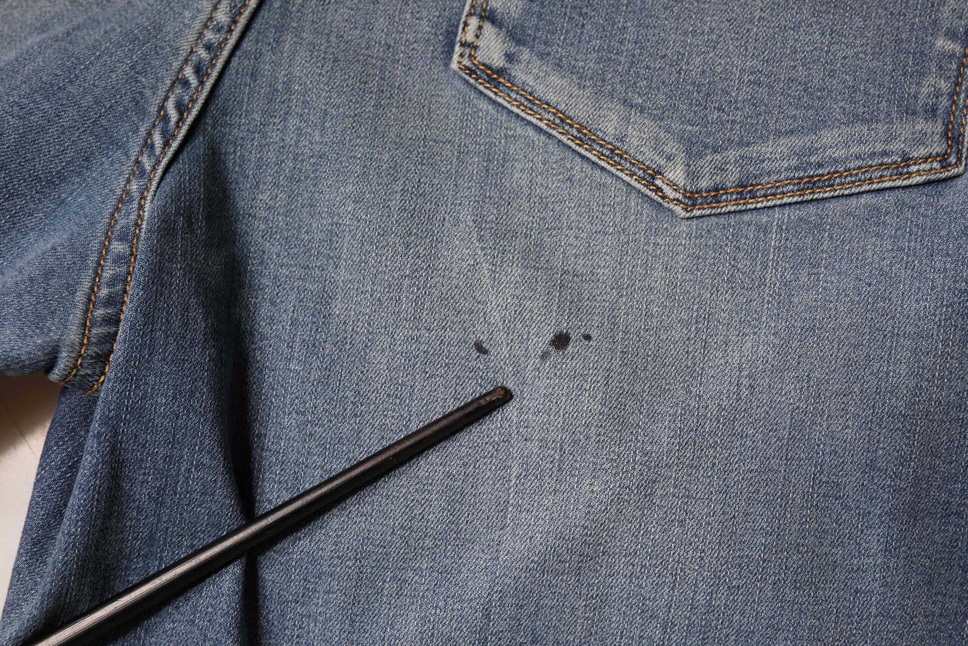 Blue denim jeans with a black mark on the left knee area