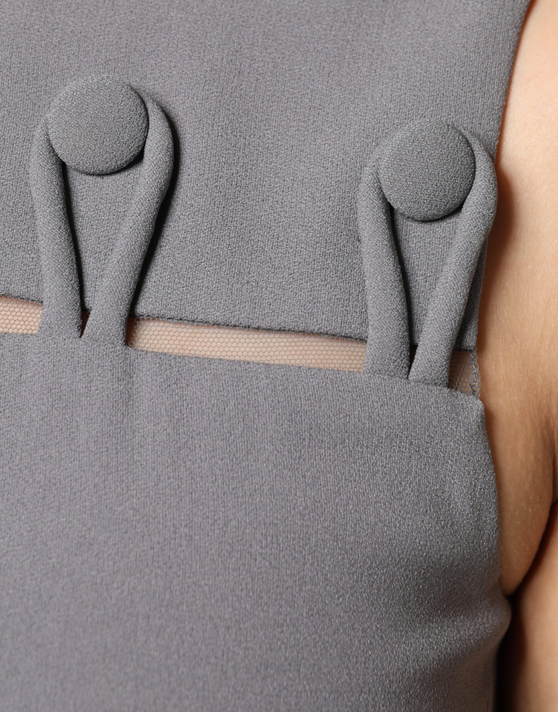 A gray sleeveless dress with a round neck and a fitted waist. It features two decorative buttons on the front