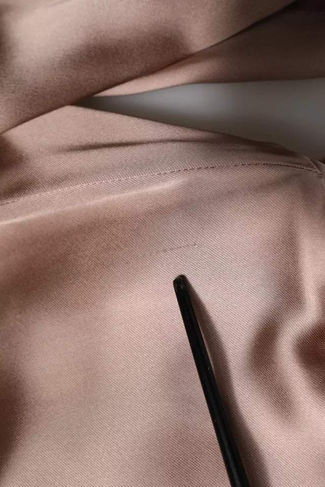 A pink satin long sleeve sheath wrap mini dress with a black pen resting on it