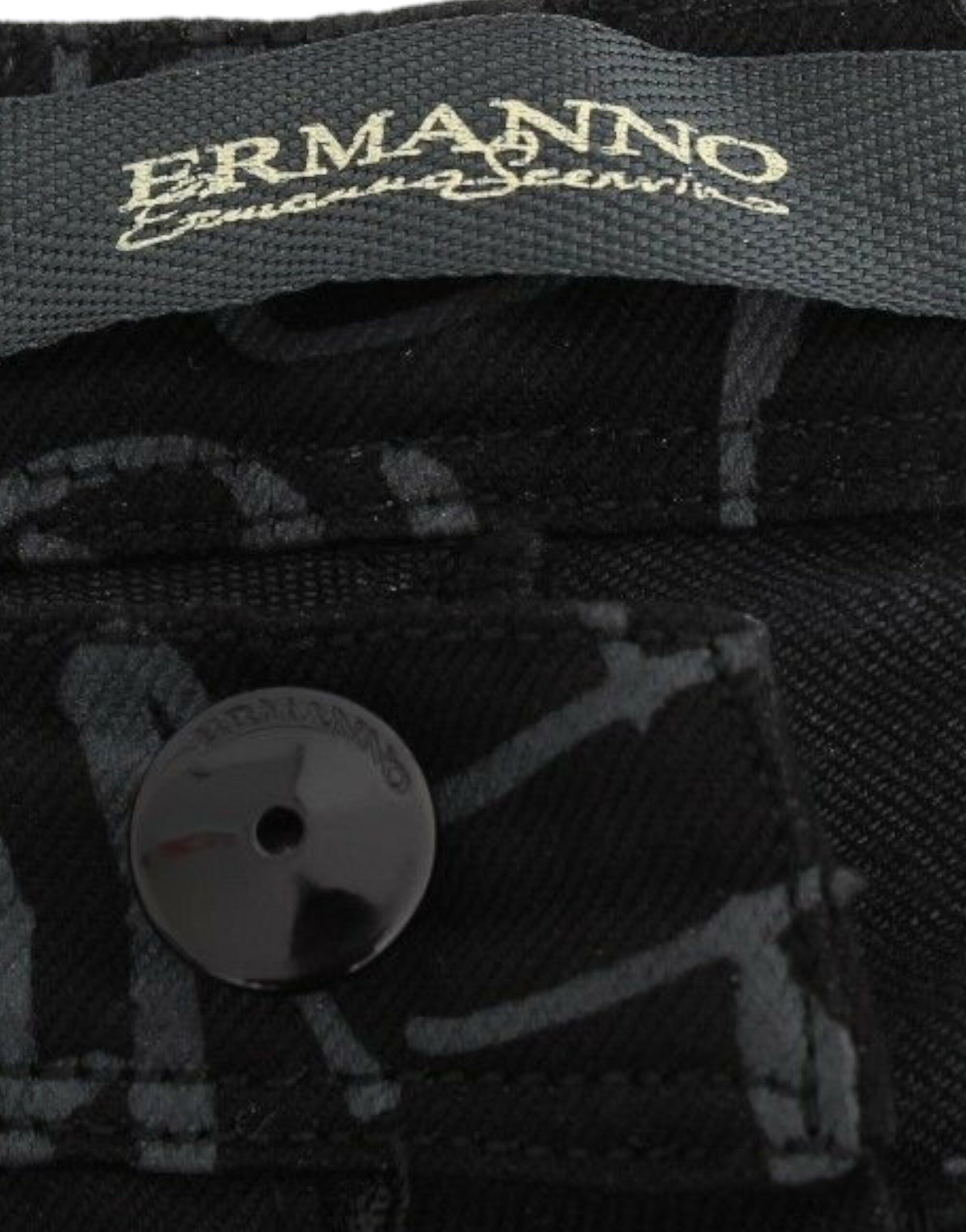 Black and white button on black fabric with embroidered pattern