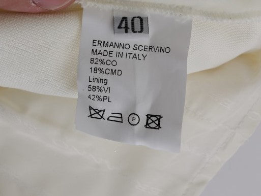 White tag on fabric with black lettering indicating brand, country of origin, material composition, care instructions, and si