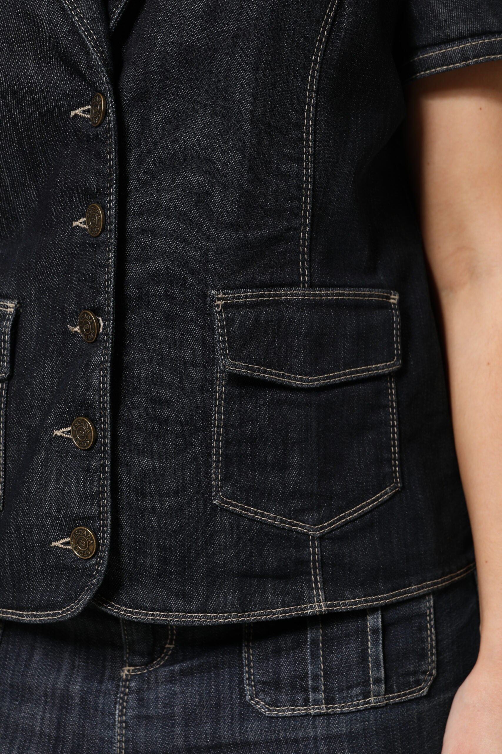 Denim vest with button details on a person's torso