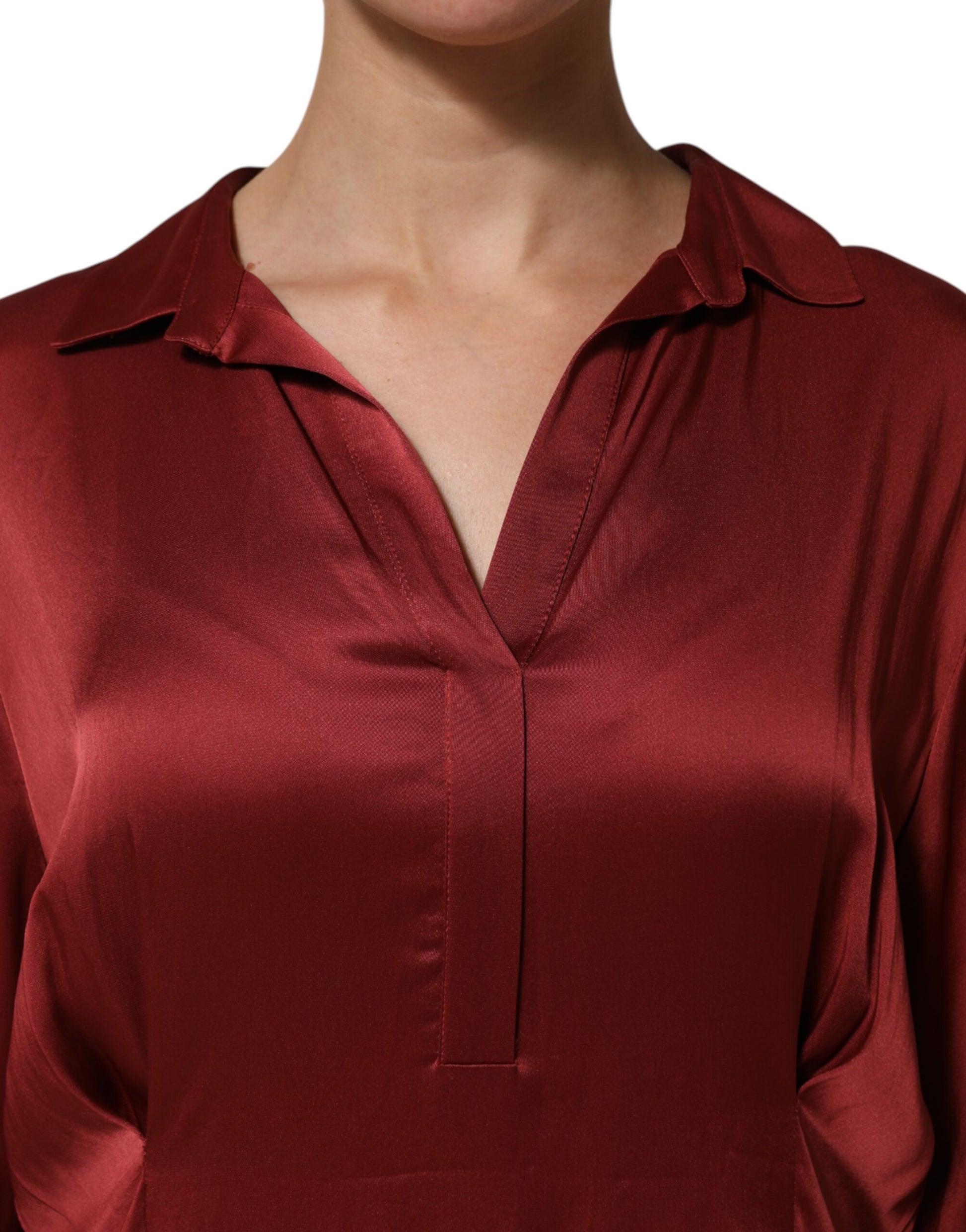 A woman wearing a burgundy satin dress with long sleeves and a V-neckline