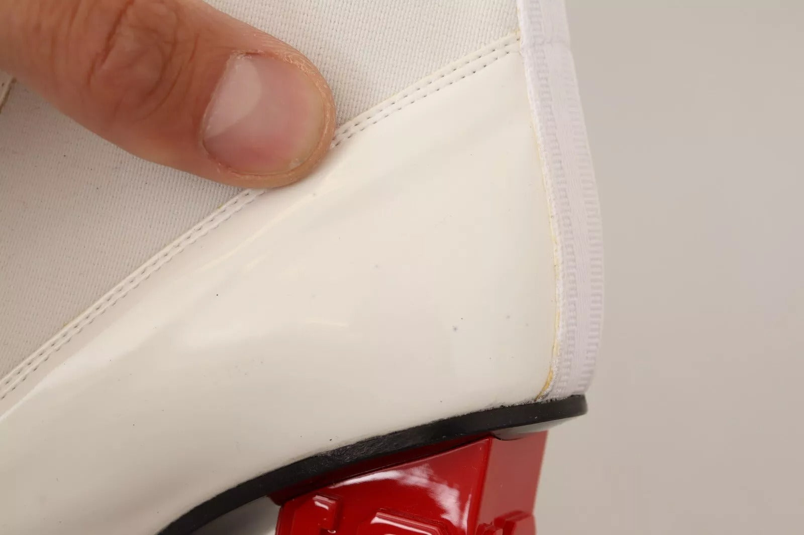 Hand holding white shoe with red accents