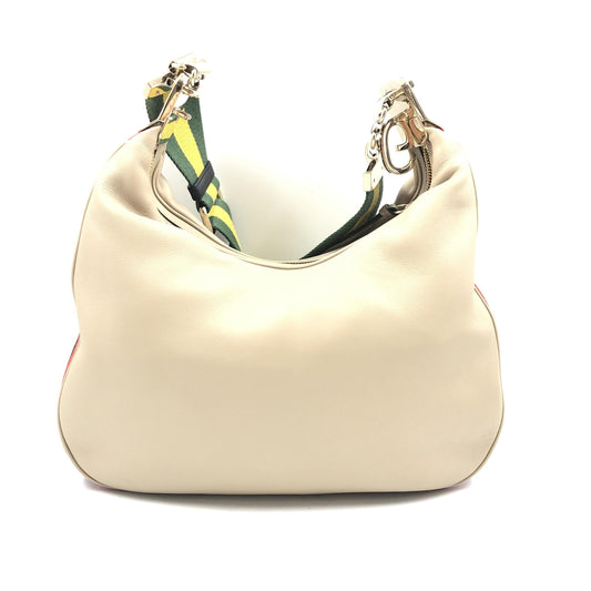 Large tan purse with gold accents and a patterned strap