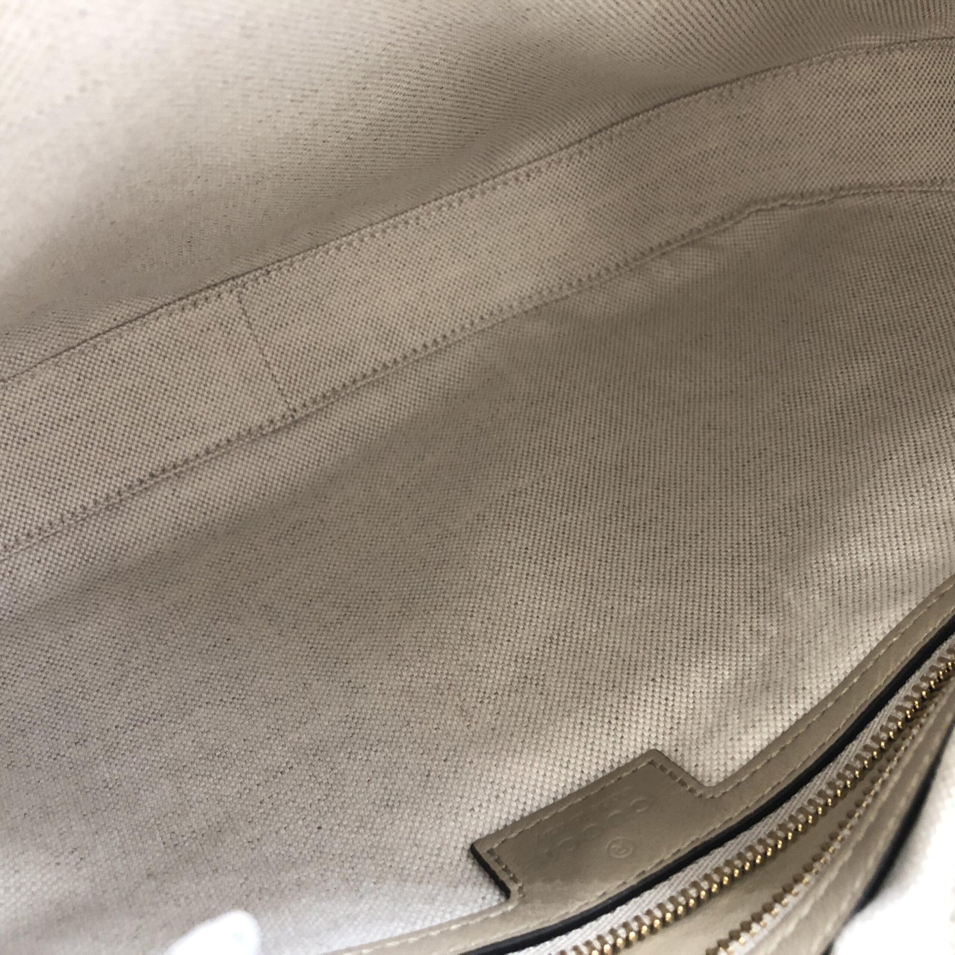 A close-up view of a fabric item with visible stitching and a zipper pull