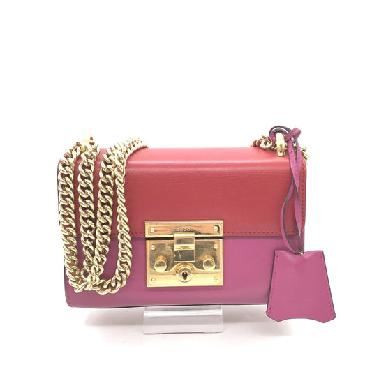 Pink purse with gold chain necklace hanging from handle
