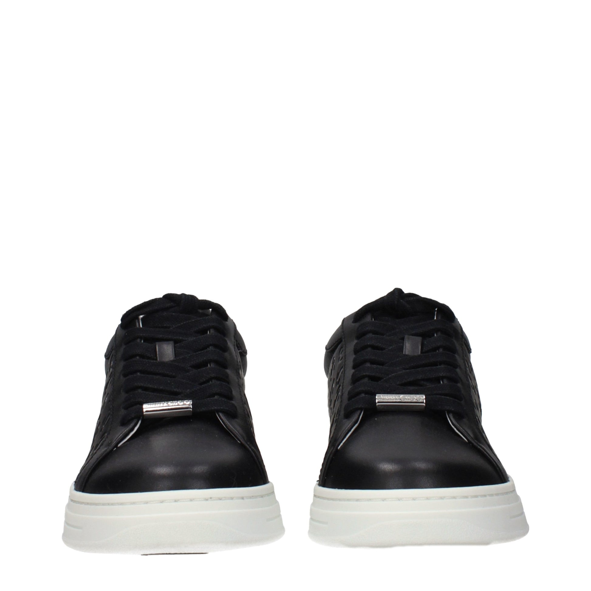 Pair of black leather sneakers with white soles, featuring a silver buckle on the side