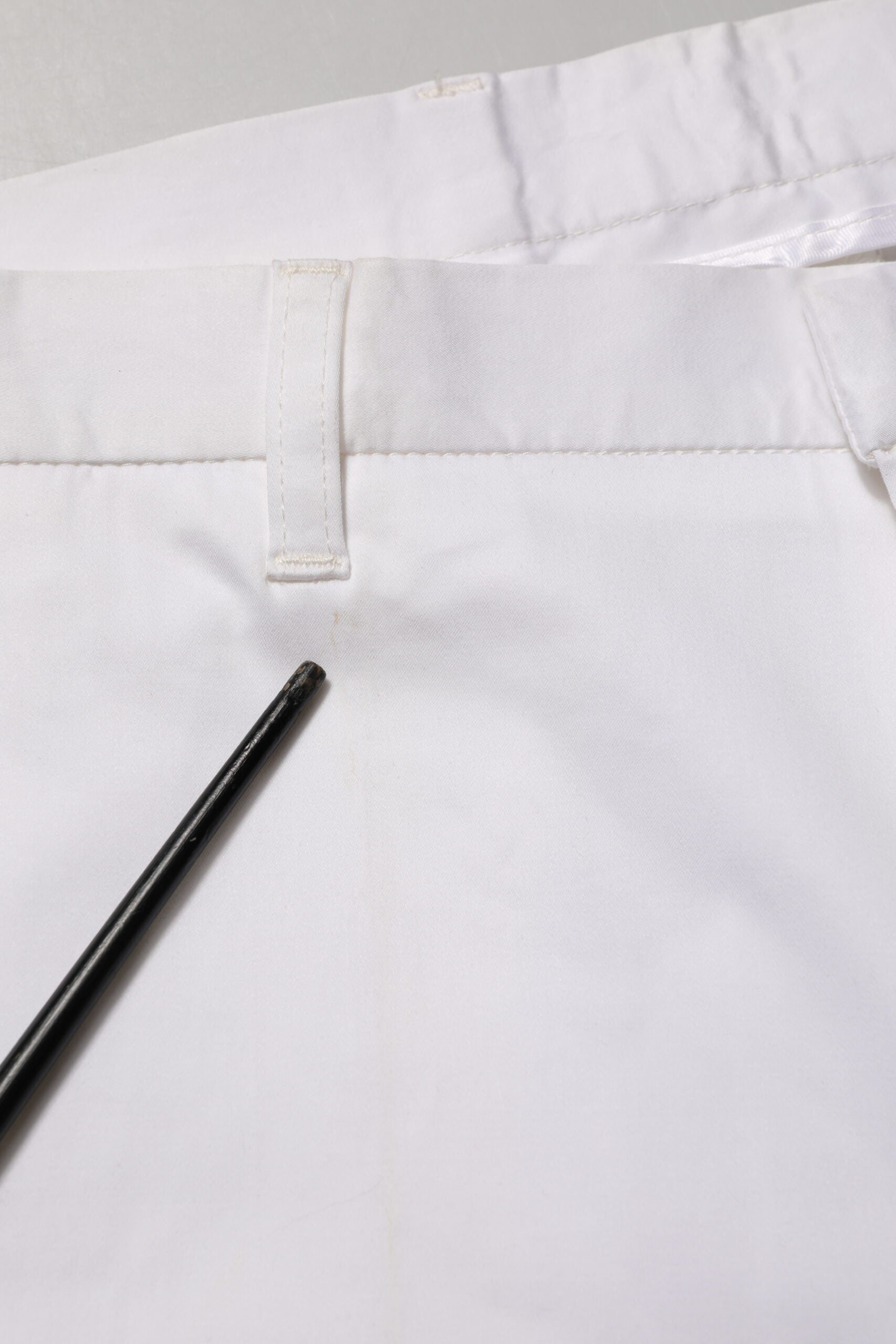 A pair of white cotton stretch dress pants with a black zipper fly