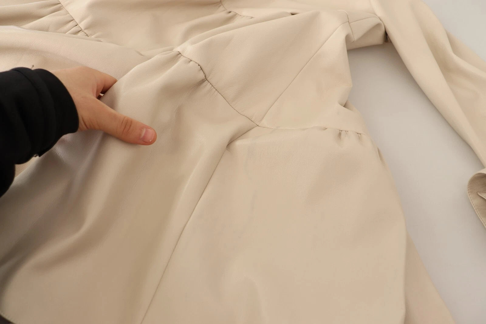 A beige leather dress with long sleeves and a collar. It is an A-line mini dress, featuring visible stitching