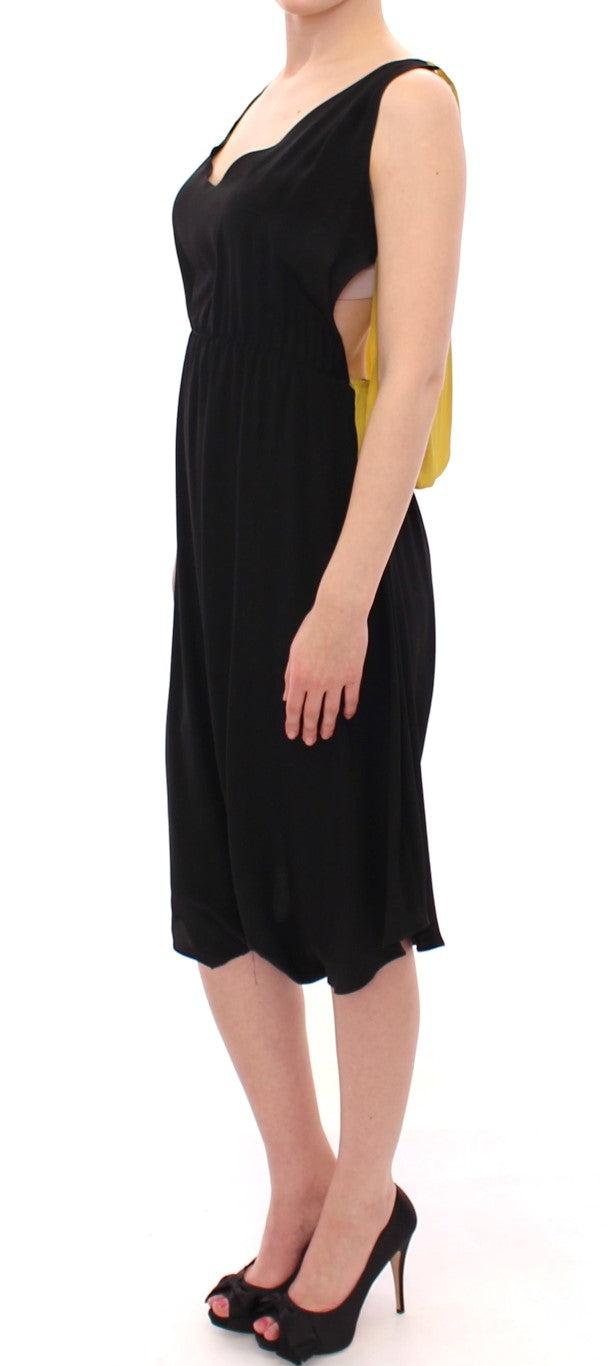 Black dress with ruffled sleeves worn by a woman standing against white background