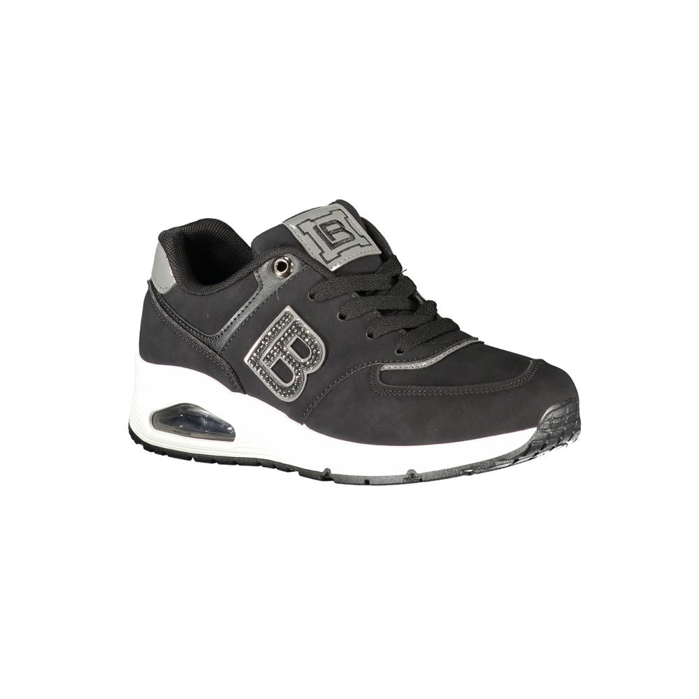 A black women's sneaker with white sole, featuring a logo on the side and a strap across the top