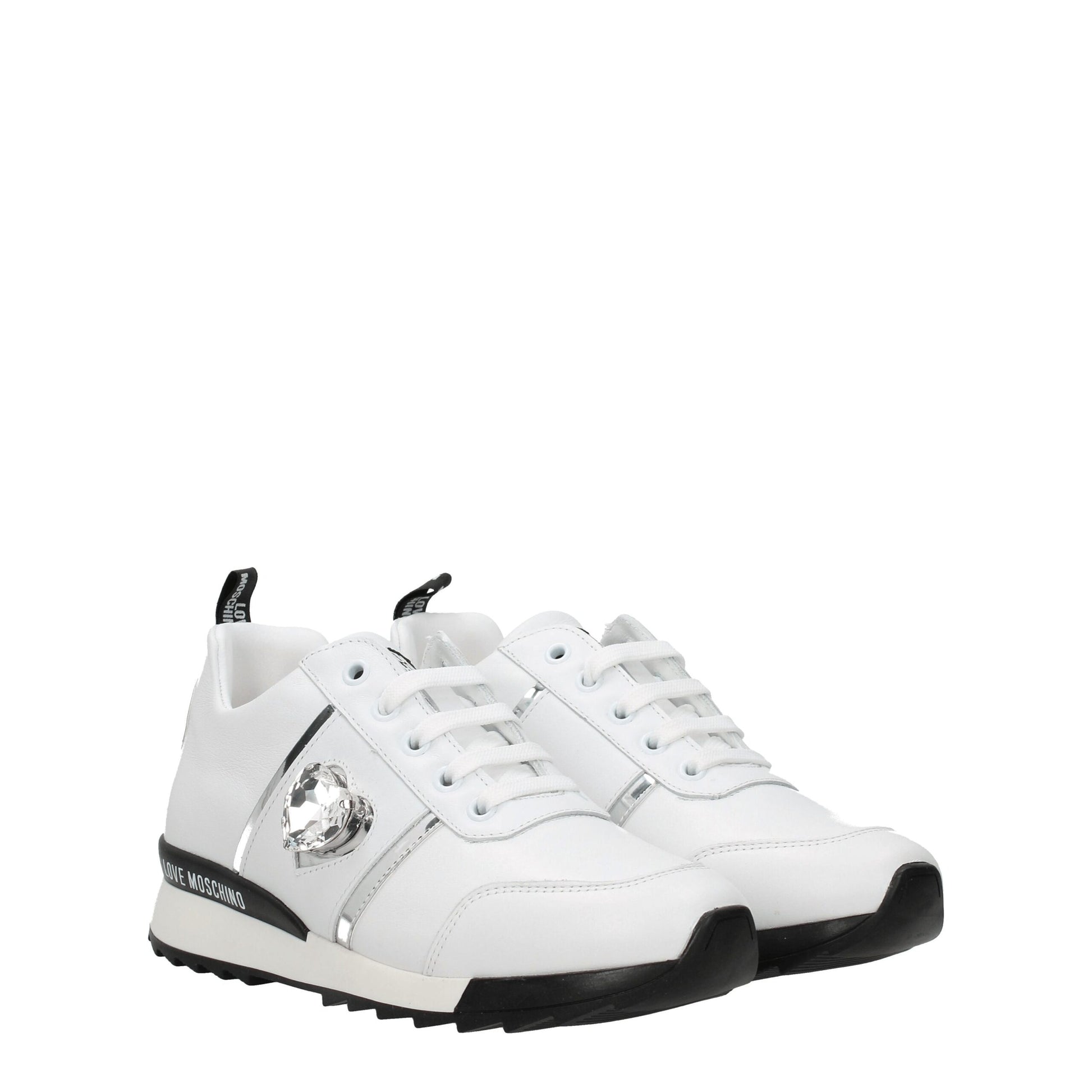 White leather low top sneakers with black laces, featuring a gold buckle and logo on the side