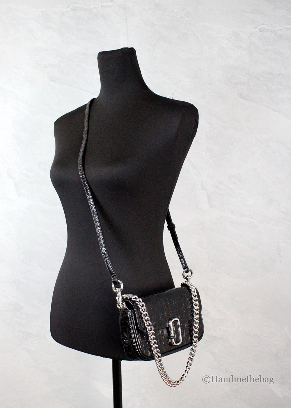 Black mannequin wearing a black purse with silver chain details
