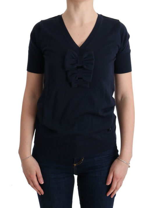 Woman wearing dark blue sweater with bow detail on front