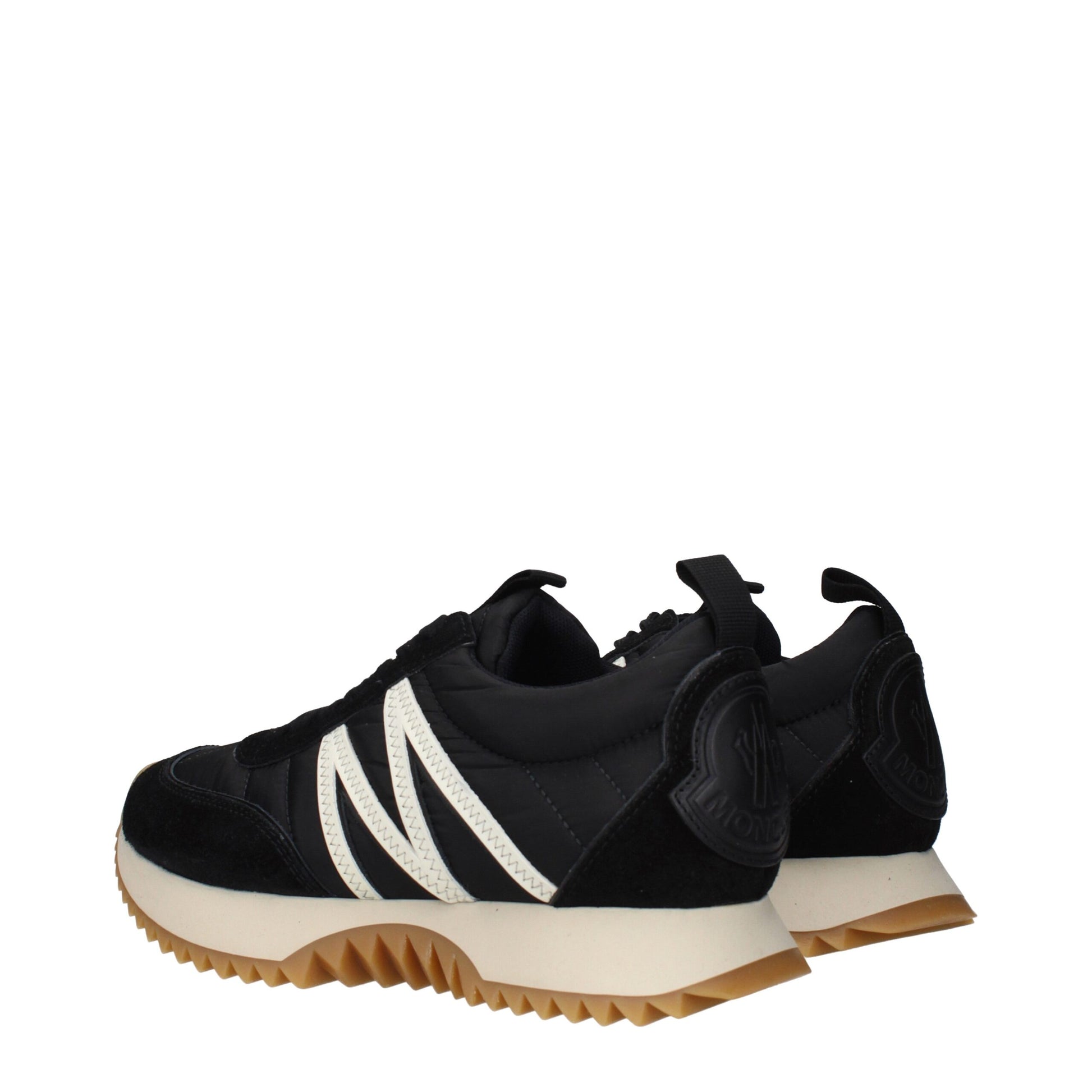 A pair of black sneakers with white stripes on the side, featuring a low top and a rubber sole with a textured pattern