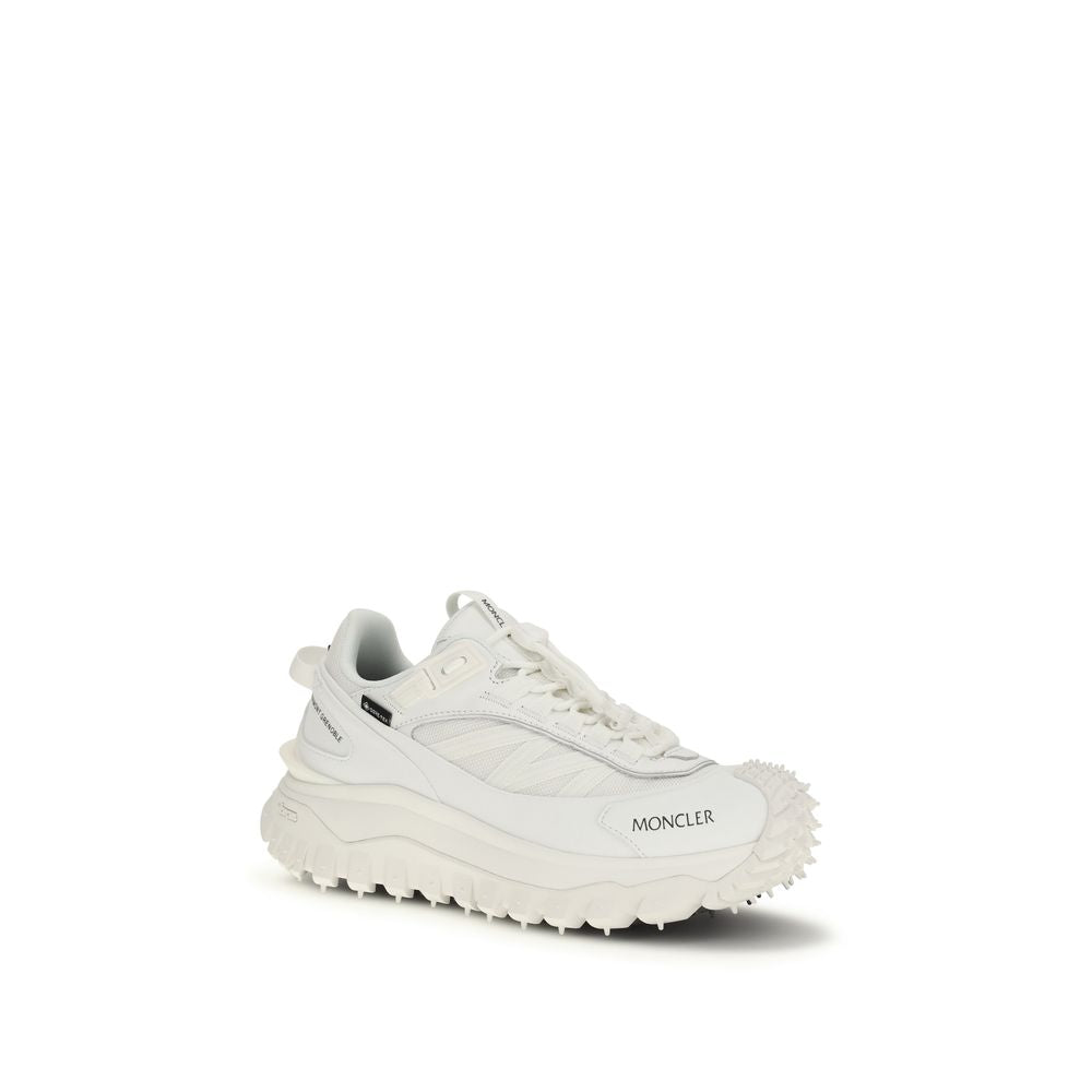 A pair of white athletic sneakers with a textured sole, featuring the brand name "Moncler" on the side