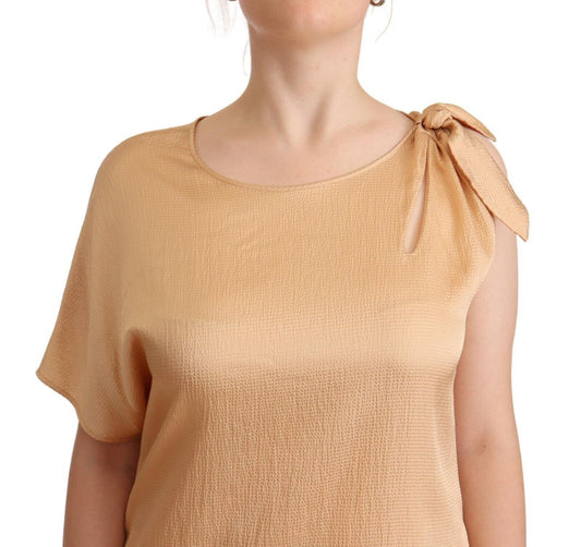 A beige one sleeve knee length shift dress with a bow on the shoulder