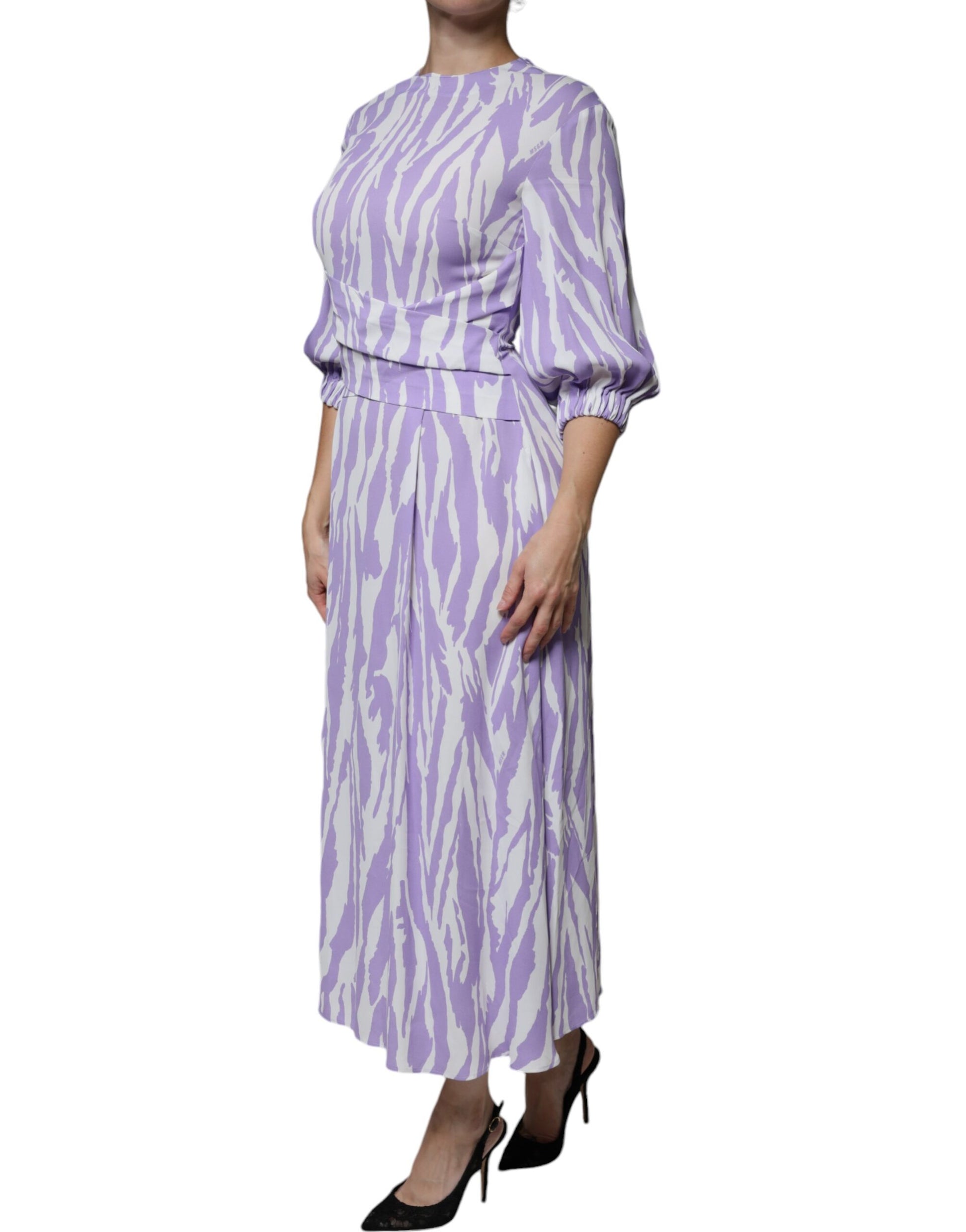 A woman wearing a long purple and white patterned dress with short sleeves