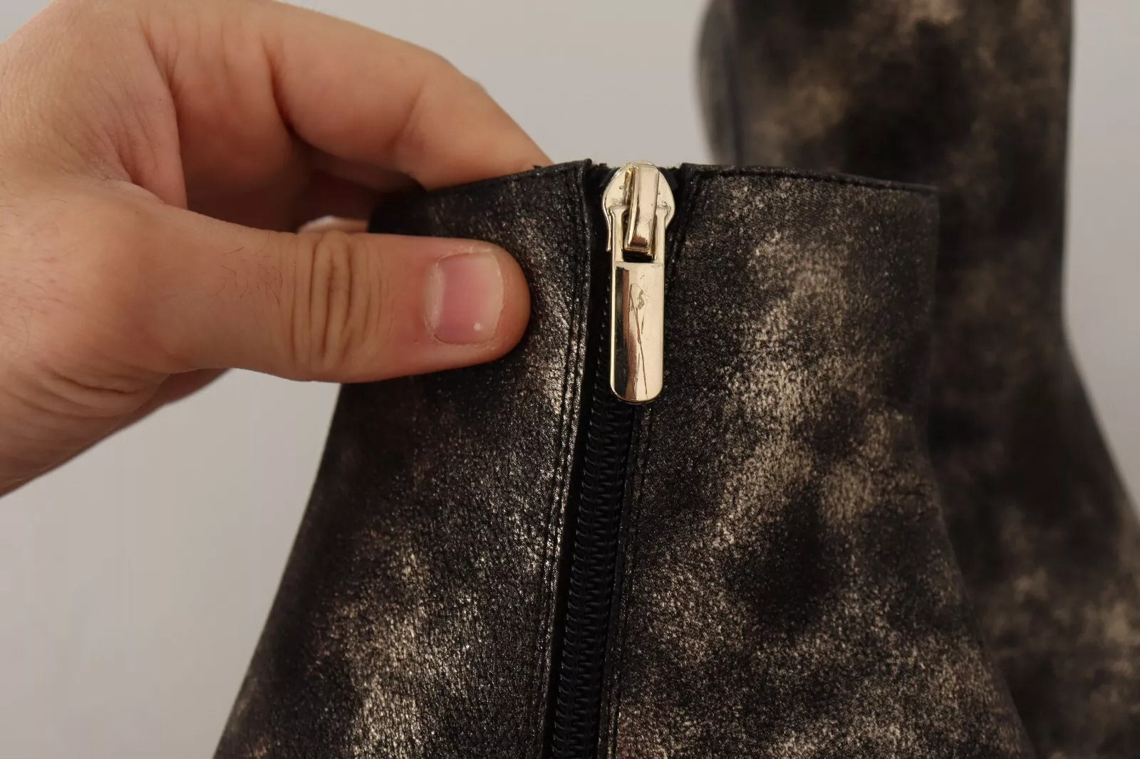 Hand holding a zipper pull on a black boot