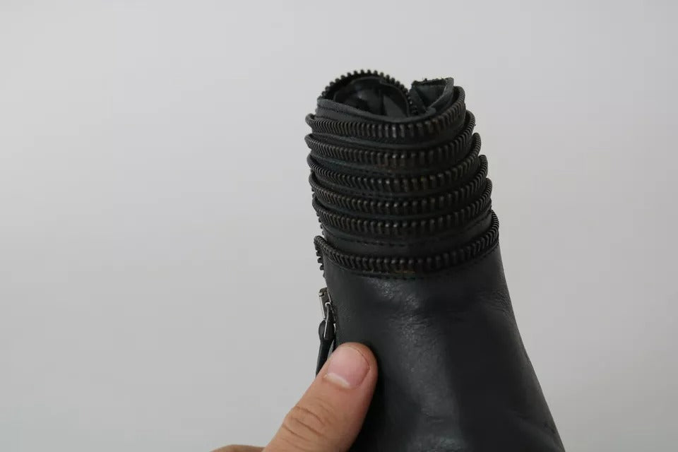Hand holding a black leather boot with zipper