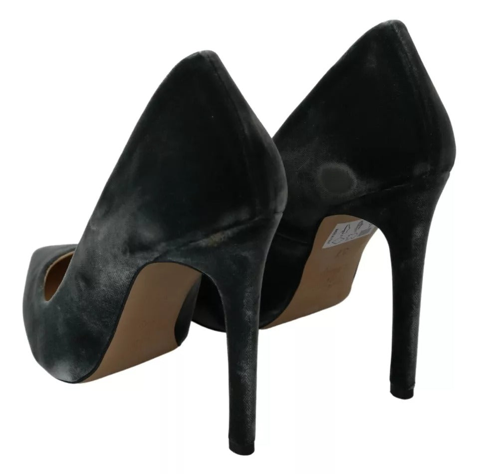 A pair of black velvet stiletto pumps with a round toe and a visible tag on the insole