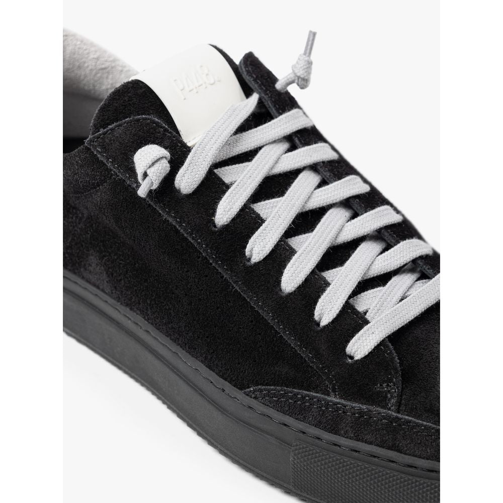 Black velvet sneaker with white laces and a label on the tongue
