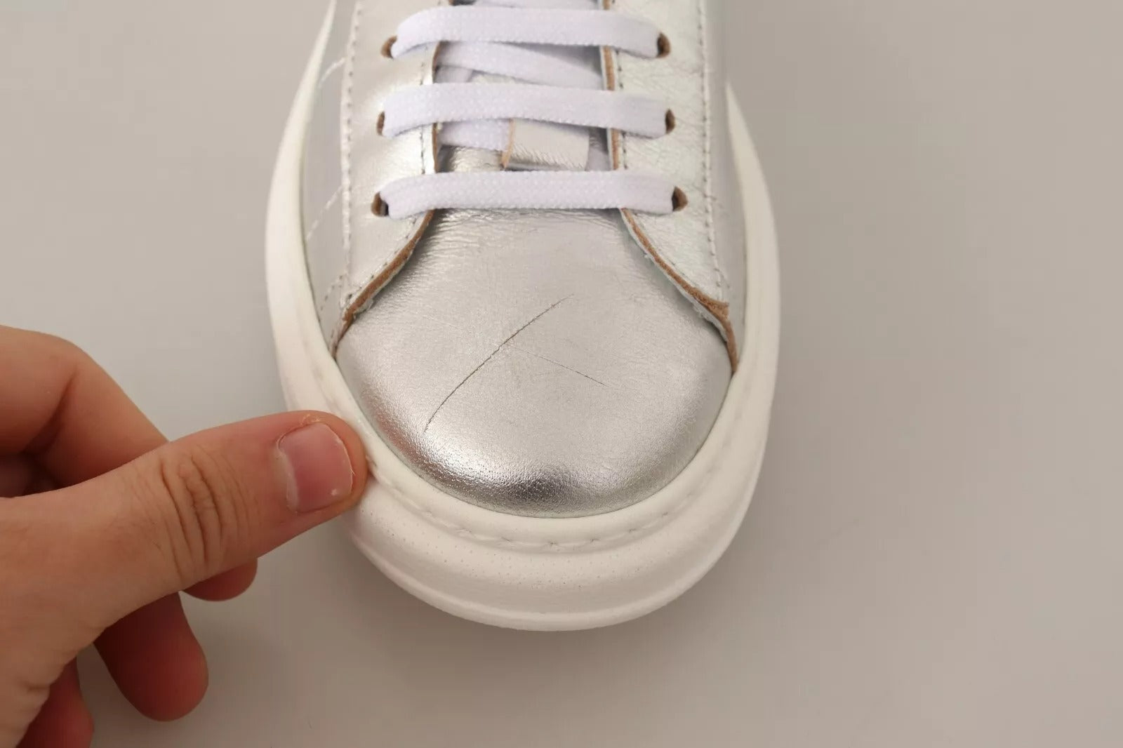 Hand holding baby shoe with silver toe cap