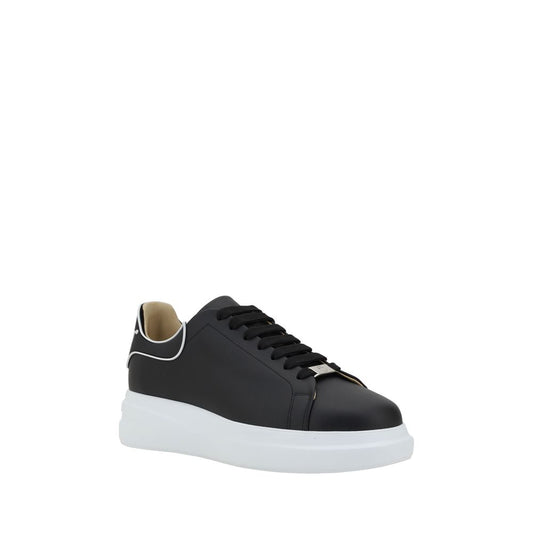A pair of black calf leather sneakers with white sole, featuring a gold buckle and logo