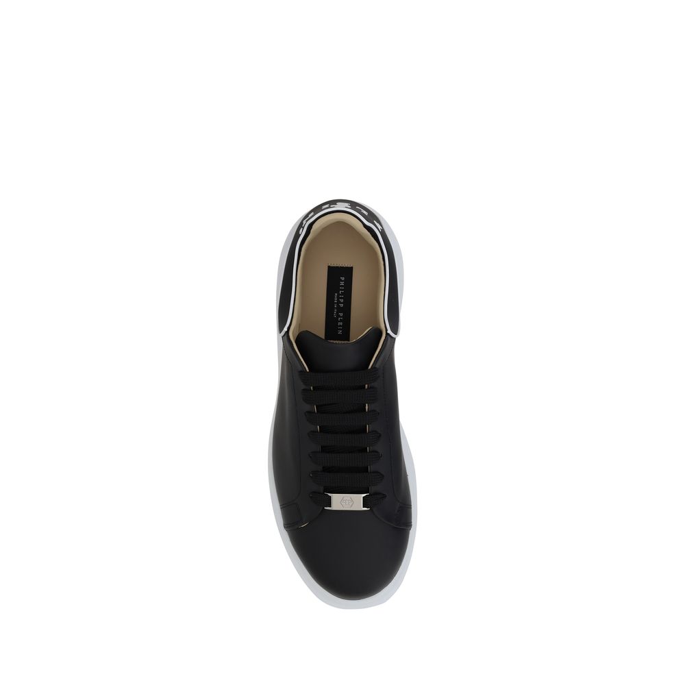 A pair of black calf leather sneakers with a low top and white sole, featuring a gold buckle on the side