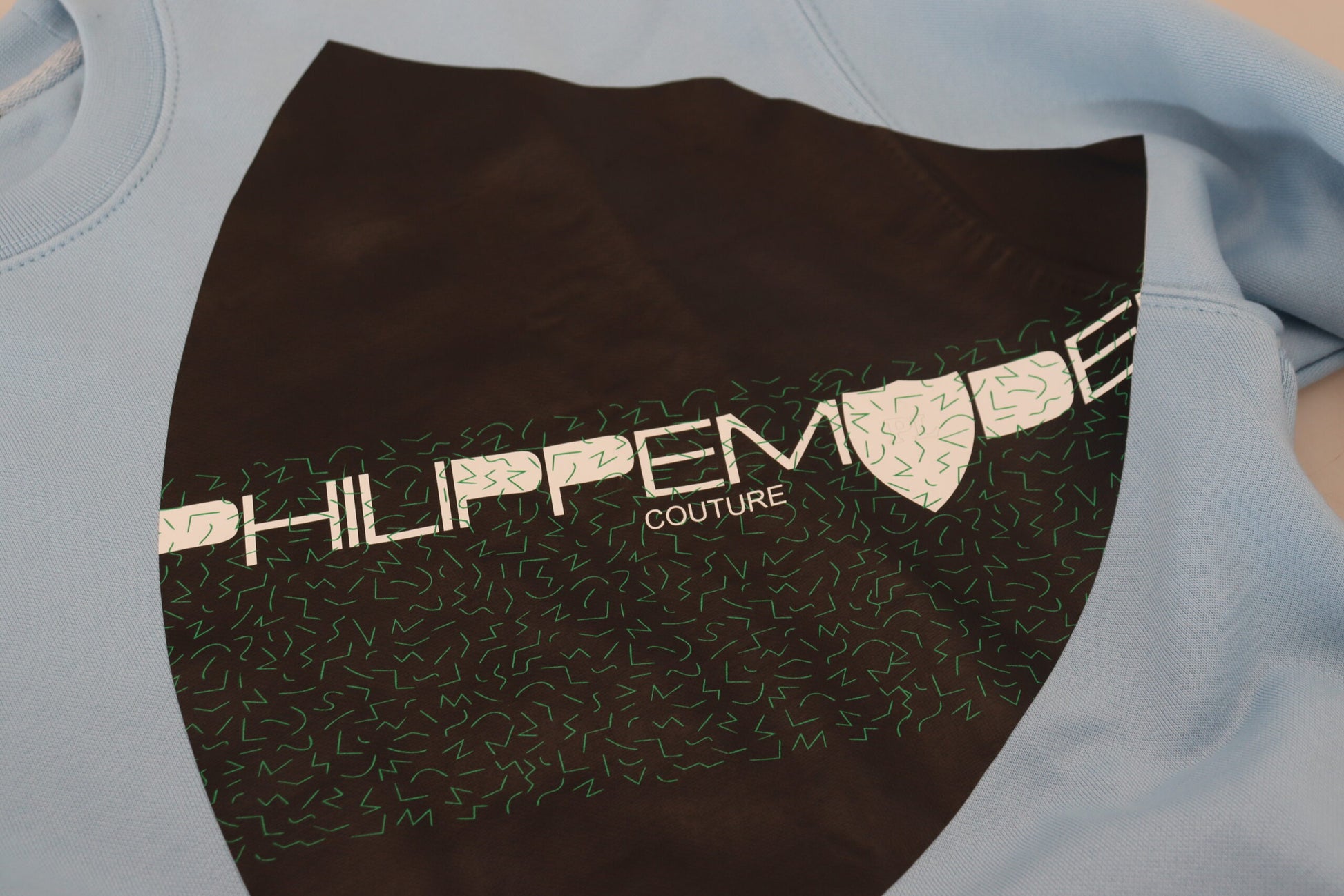 Blue sweatshirt with black sleeves and green lettering