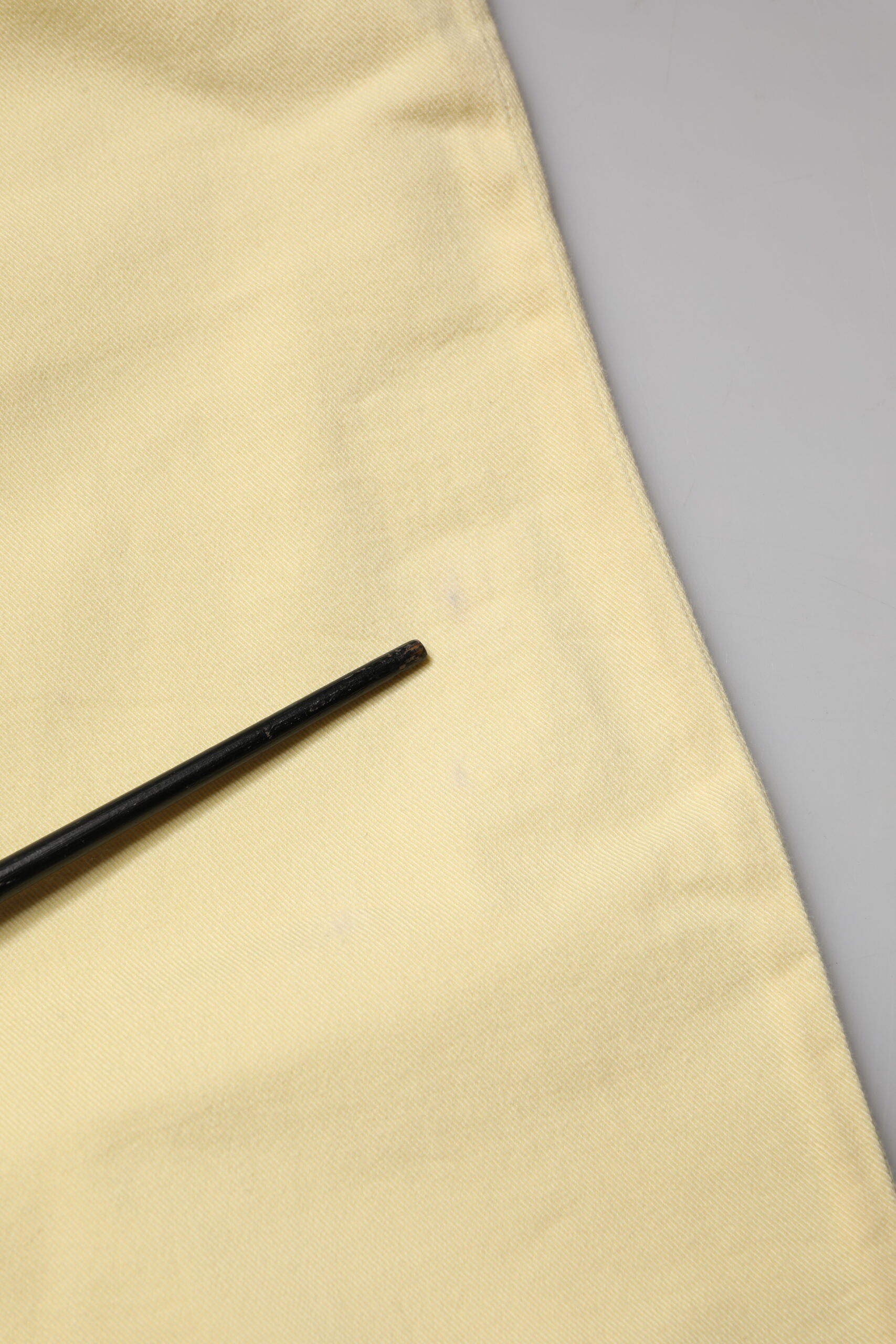 Black sewing needle on yellow fabric