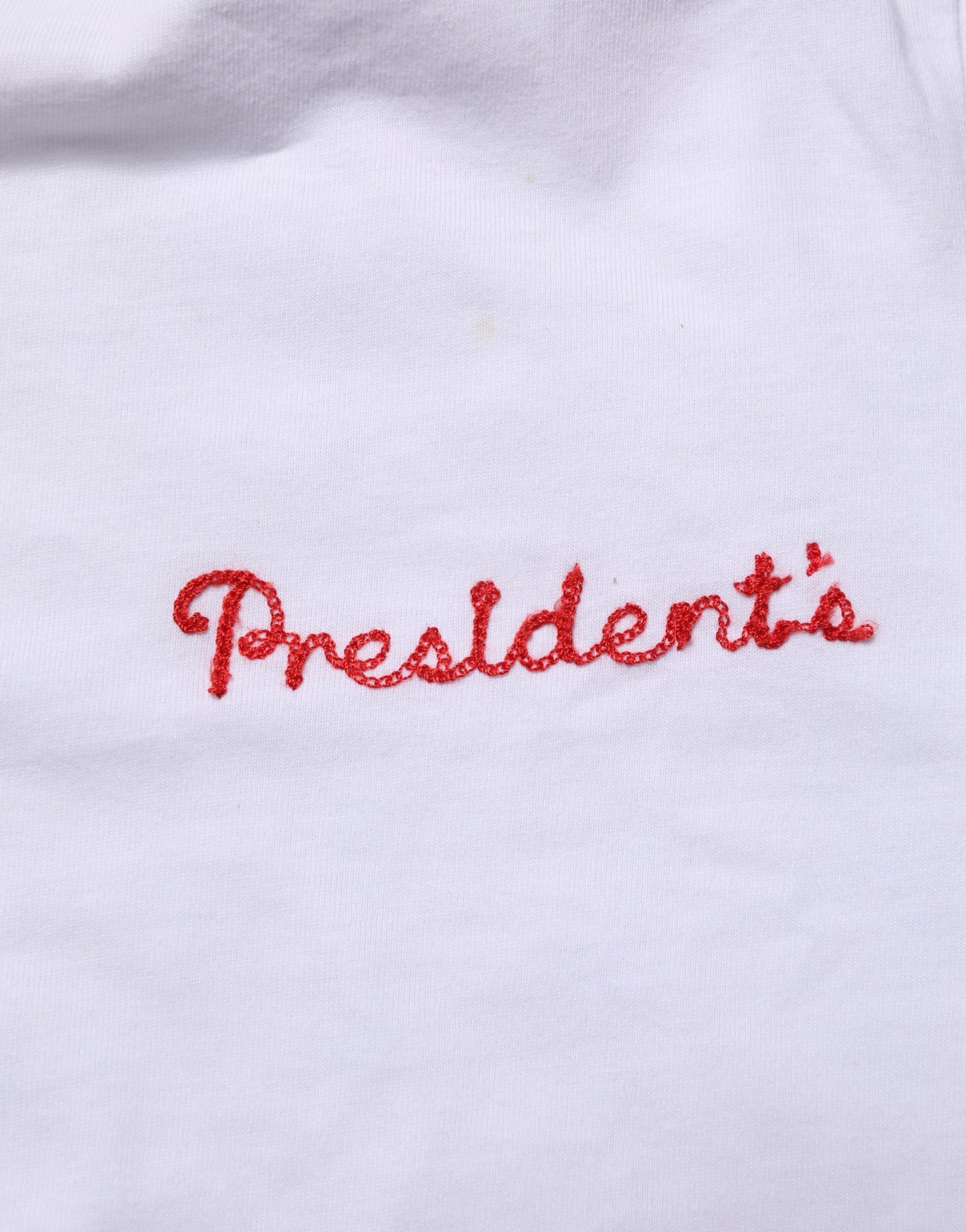 Red embroidered president's on white fabric