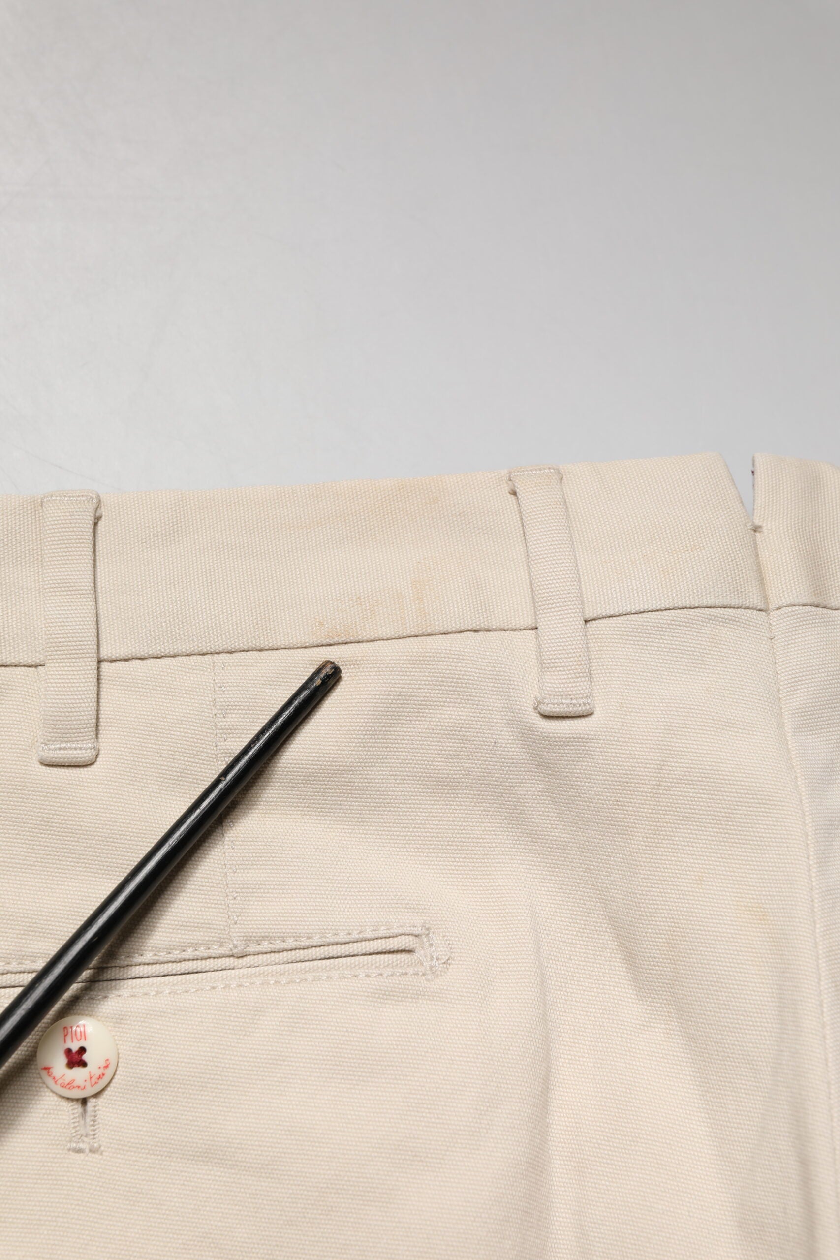 Tan men's chino pants with black zipper and button
