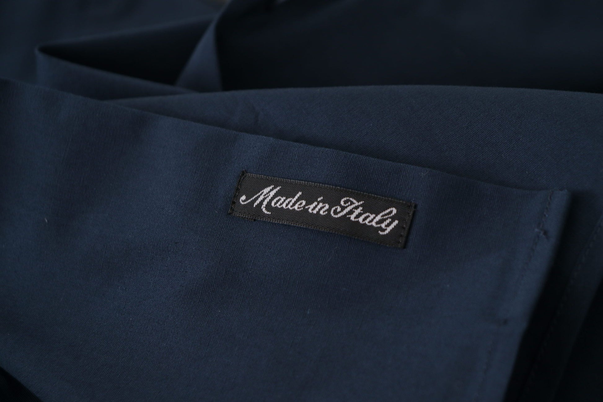 A navy blue cotton dress shirt with a label that reads "Made in Italy"