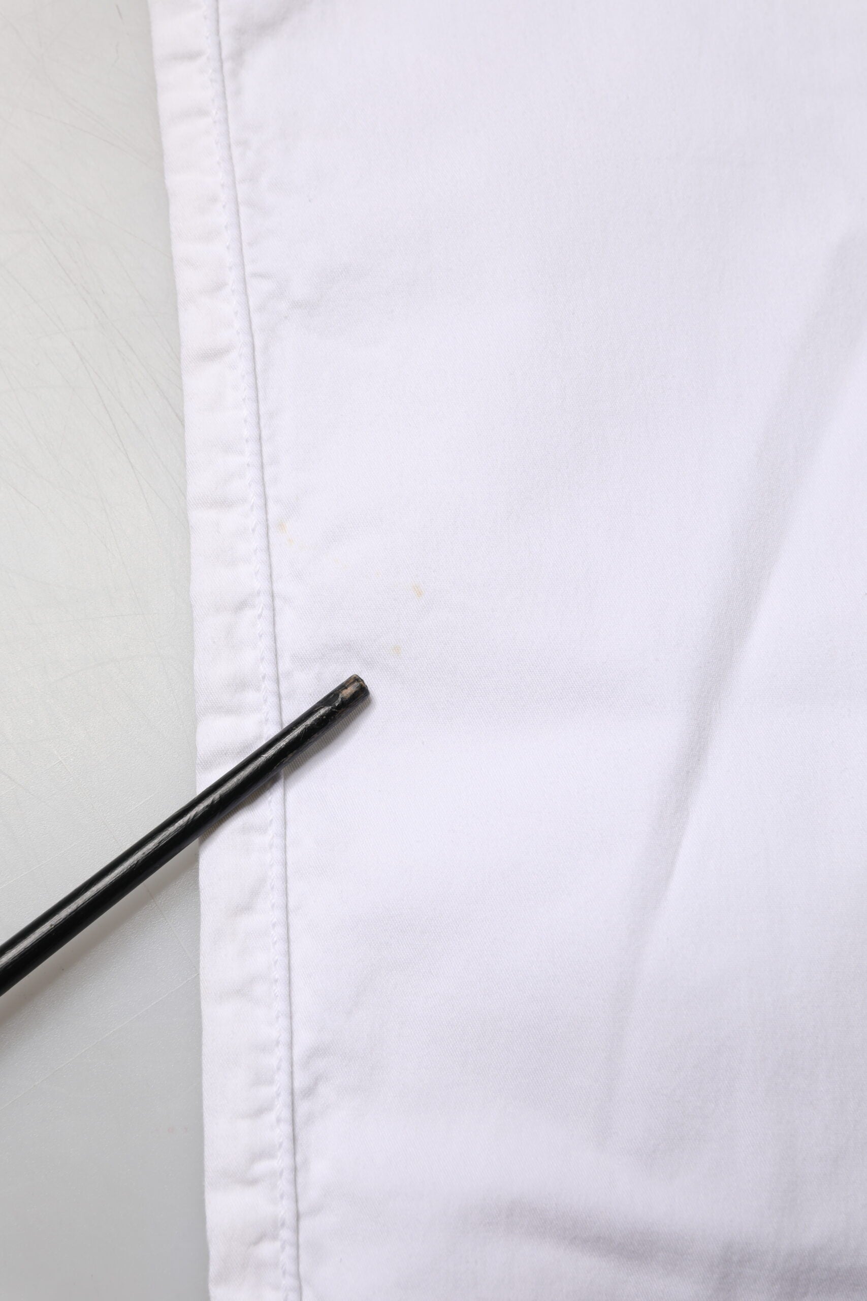 White fabric with buttonhole and pin