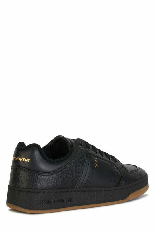 Black sneaker with white sole and yellow logo on side