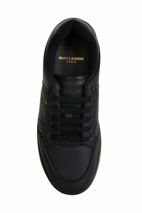 Black sneaker with yellow logo on side and sole