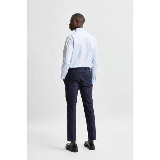 A mannequin wearing a blue dress shirt with rolled-up pants, standing against a white background