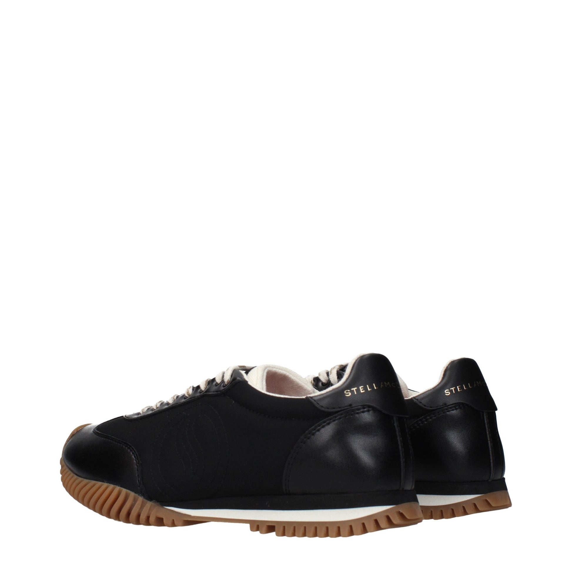 A pair of black fabric low top sneakers with white laces, featuring a white sole and brown trim around the base