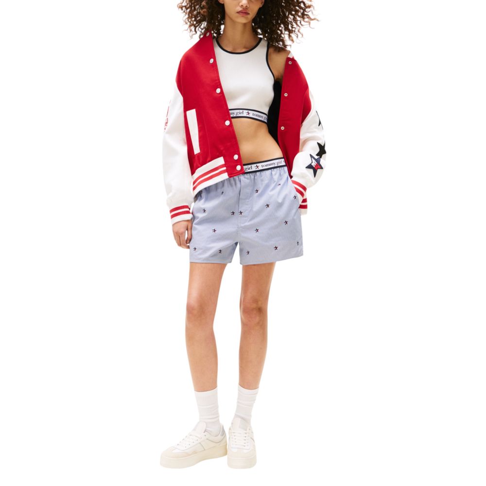 Woman wearing red jacket, white shorts, and sneakers