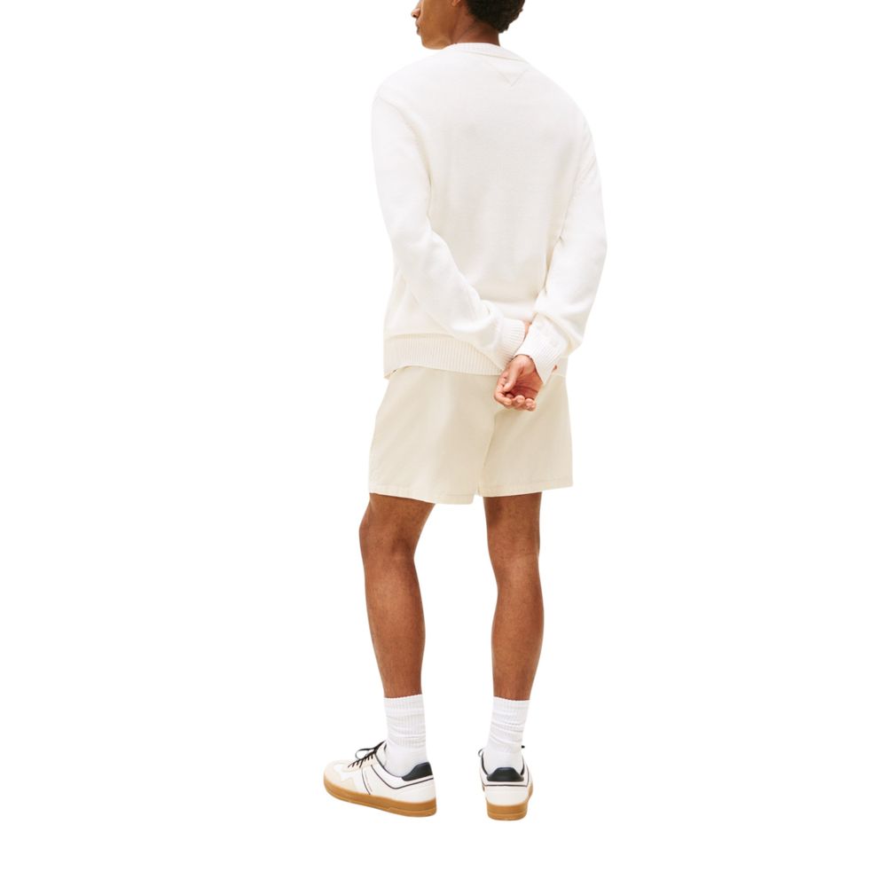 Man wearing white sweater and shorts standing against a white background