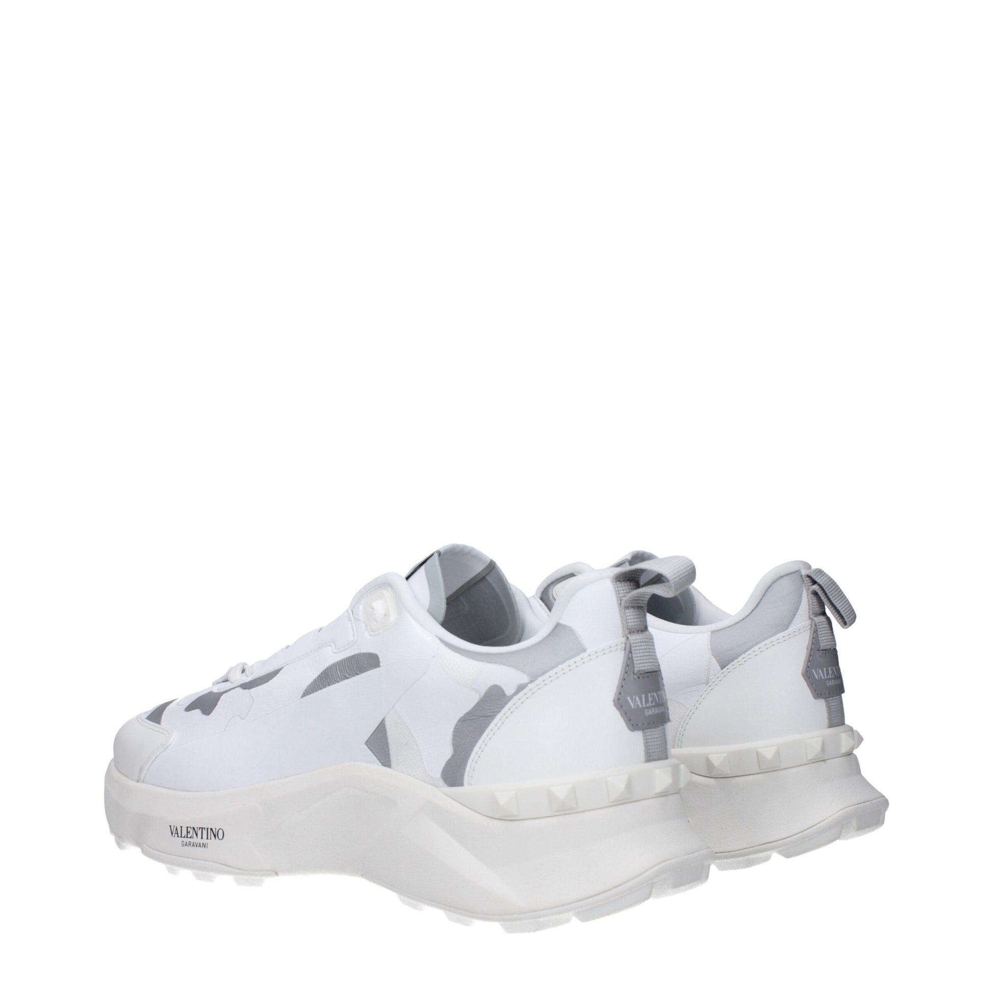 White athletic sneakers with camouflage pattern on sides, featuring laces and a chunky sole design