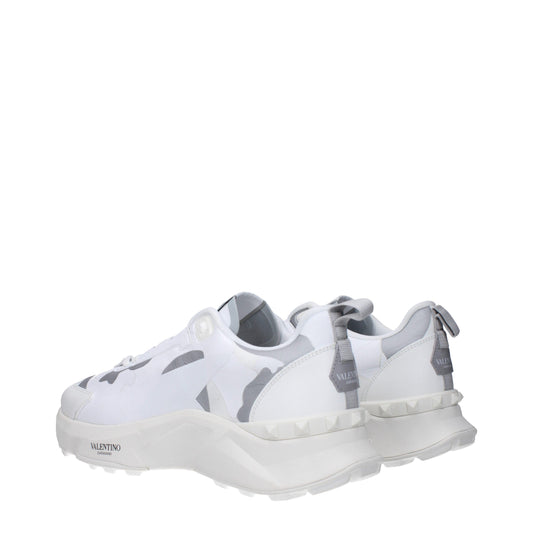 White athletic sneakers with camouflage pattern on sides, featuring laces and a chunky sole design