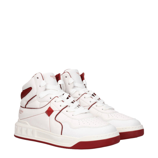White leather high top sneakers with red accents, laces, and sole