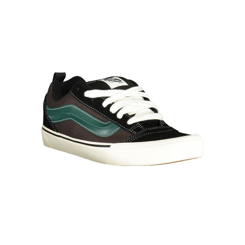 A black and white sneaker with a green stripe on the side, featuring a lace-up closure and a flat sole