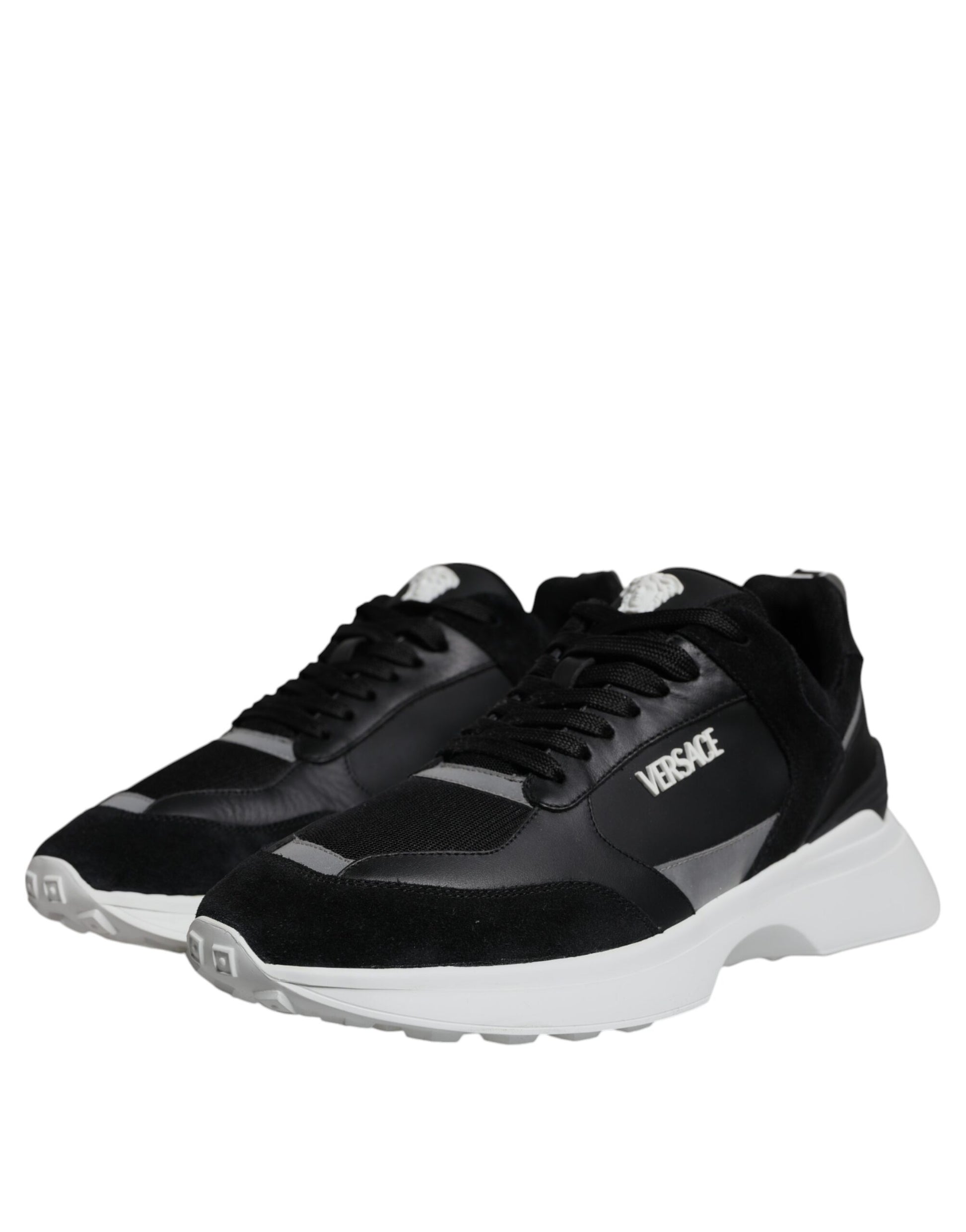 A pair of black canvas sneakers with white soles, featuring the Versace logo on the side