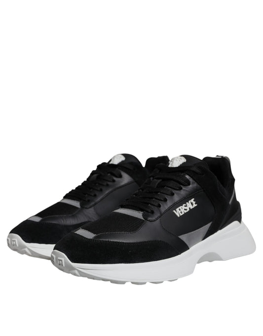 A pair of black canvas sneakers with white soles, featuring the Versace logo on the side