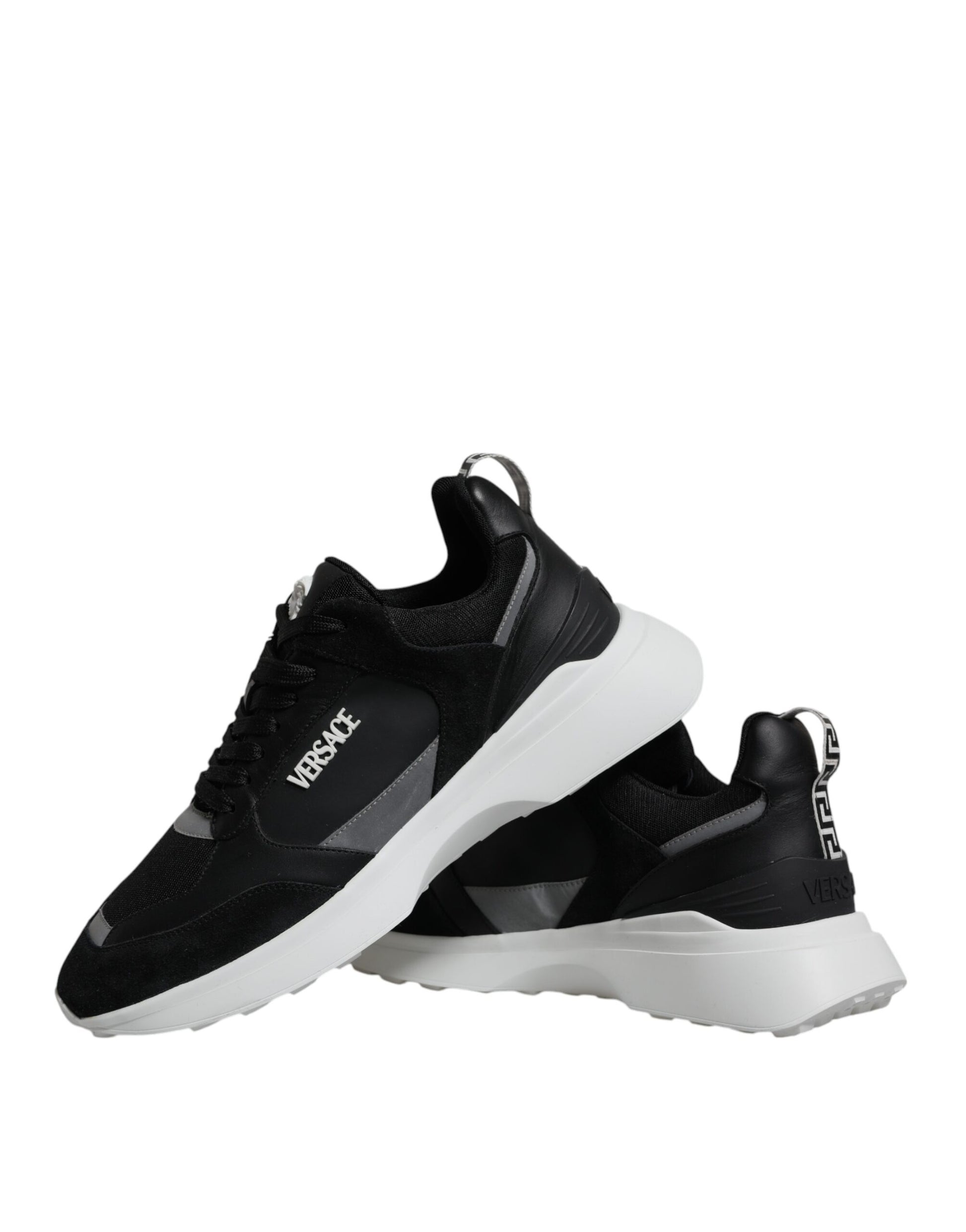 A pair of black canvas sneakers with white soles, featuring the Versace logo on the side