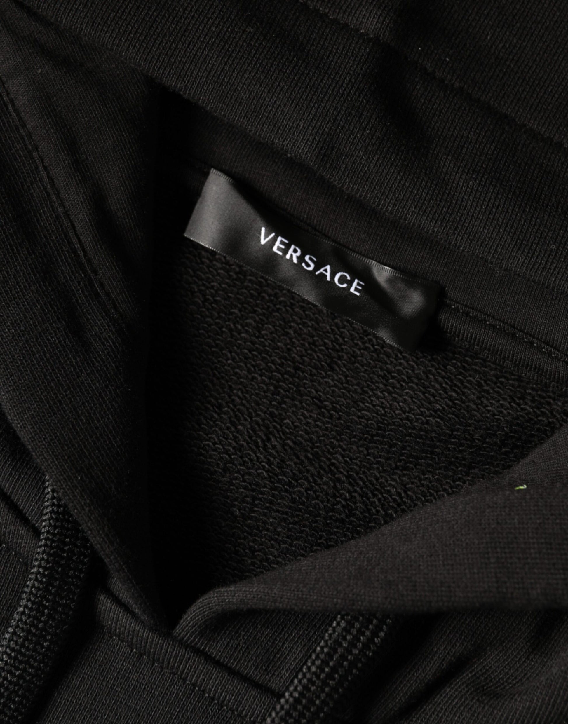 Black clothing item with white label reading "versace"